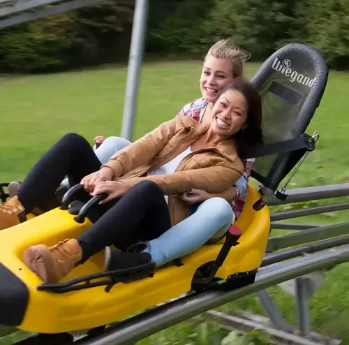 Zwei Frauen sitzen lachend im Alpine Coaster Schlitten auf der Sommerrodelbahn Gutach.