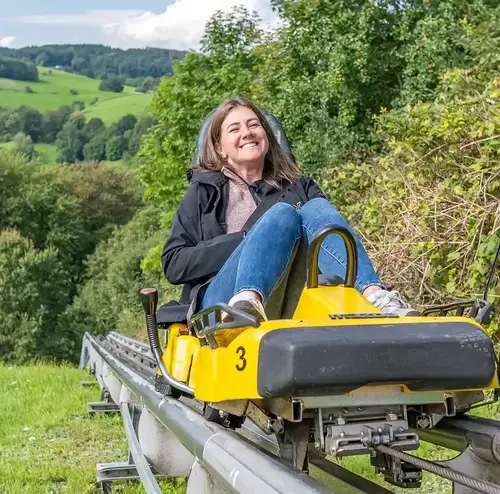 Eine Frau fährt lachend auf der Sommerrodelbahn in Gutach.