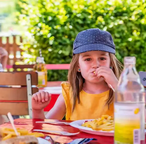 Ein Kind isst Pommes im Imbissbereich der Sommerrodelbahn Gutach.