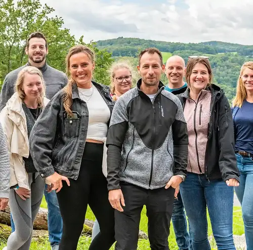 Eine Busreisengruppe steht lachend im Freizeitpark der Sommerrodelbahn Gutach in Baden-Württemberg.