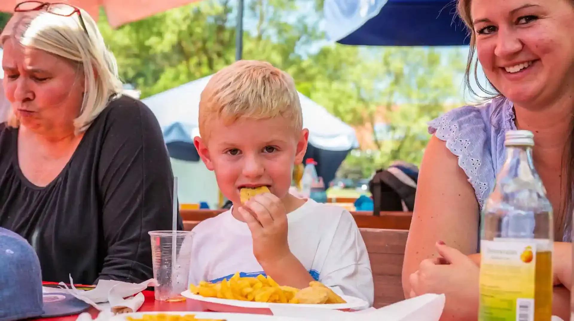Ein Kind isst Pommes und Chicken Nuggets im Imbissbereich der Sommerrodelbahn Gutach.