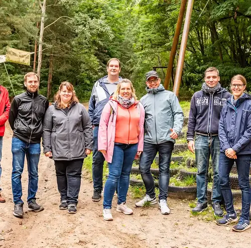 Eine Wandergruppe steht vor einem Wald am Standort der Sommerrodelbahn Gutach.