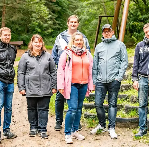 Eine Busreisegruppe posiert für ein Foto vor einem Wanderweg im Schwarzwald.