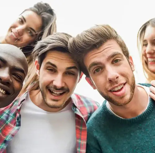 Eine Gruppe junger, lachender Menschen macht ein Selfie. 