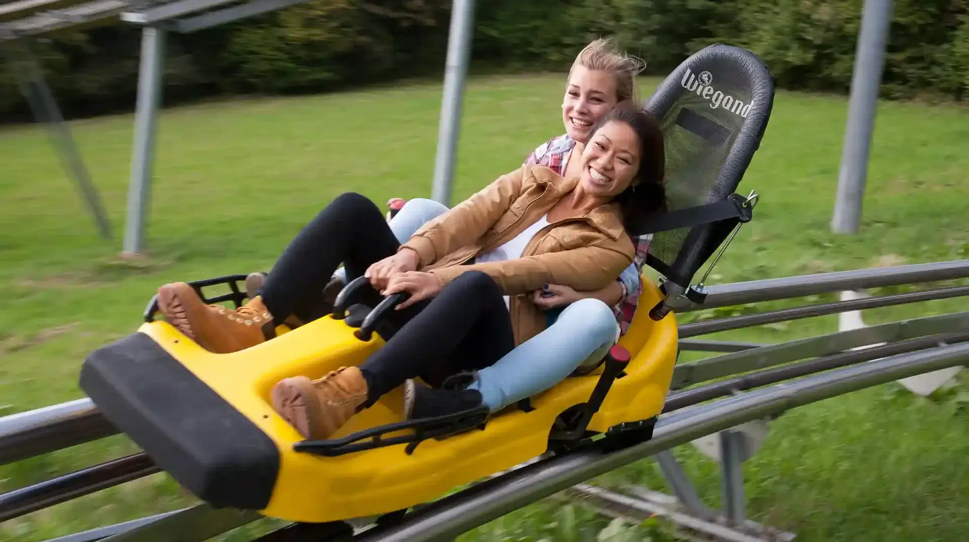 Zwei junge Frauen auf einem Schlitten einer Sommerrodelbahn im Schwarzwald in Gutach.