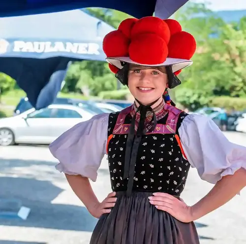 Eine Frau steht im Biergarten der Sommerrodelbahn Gutach und trägt einen Bollenhut der Schwarzwälder Tracht.