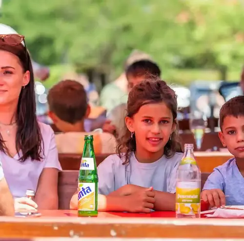Eine Familie sitzt bei Sonnenschein im Imbissbereich der Sommerrodelbahn Gutach.