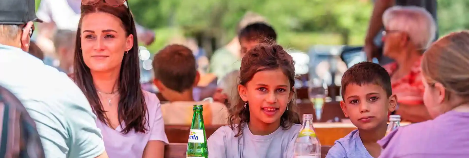 Eine Familie sitzt bei Sonnenschein im Imbissbereich der Sommerrodelbahn Gutach.